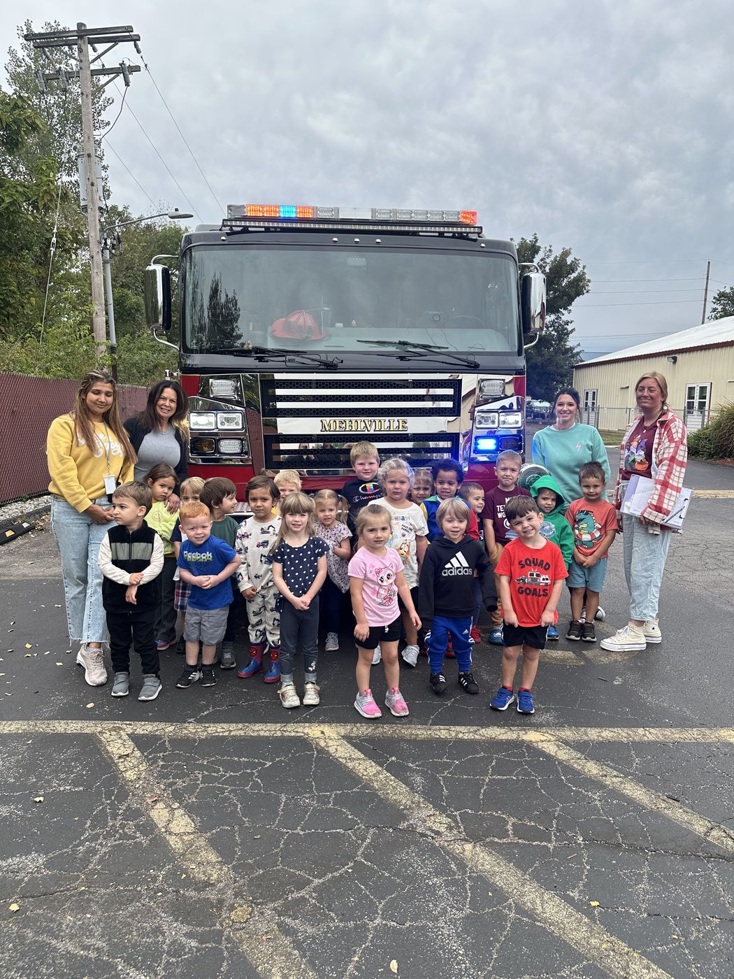 A class of children and their teachers pose in front of a Mehlville fire engine.